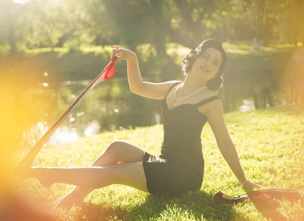 Vacker ung kvinna med pin-up make-up och frisyr poserar i sommar stadsparken — Stockfoto