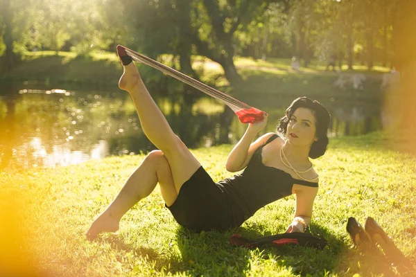 Hermosa mujer joven con pin-up maquillaje y peinado posando en el parque de la ciudad de verano — Foto de Stock