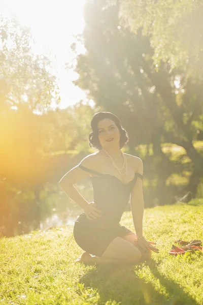 Vacker ung kvinna med pin-up make-up och frisyr poserar i sommar stadsparken — Stockfoto