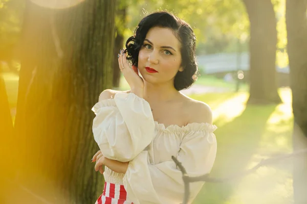 Junge schöne kaukasische Frau posiert im Retro-Styling. Pin-up Mädchen im weißen Hemd bei Sonnenuntergang. — Stockfoto