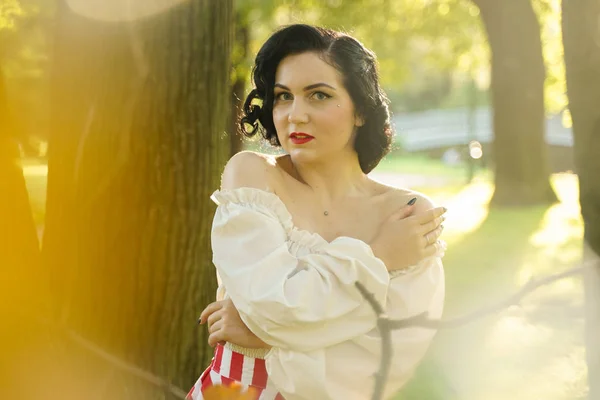 Junge schöne kaukasische Frau posiert im Retro-Styling. Pin-up Mädchen im weißen Hemd bei Sonnenuntergang. — Stockfoto