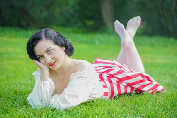 Ritratto vintage di una donna in abito retrò bianco e rosso nel parco cittadino — Foto Stock