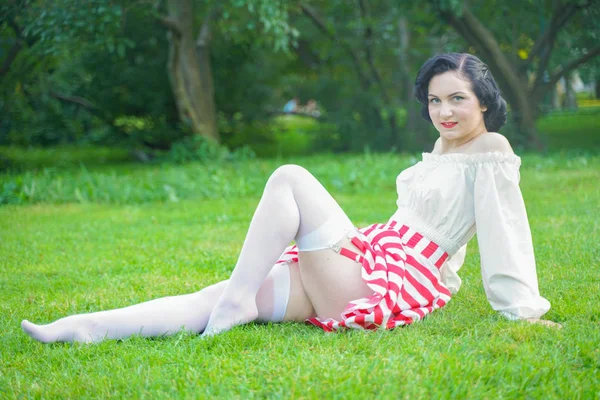 Retrato vintage de uma mulher em vestido branco e vermelho retrô no parque da cidade Imagem De Stock