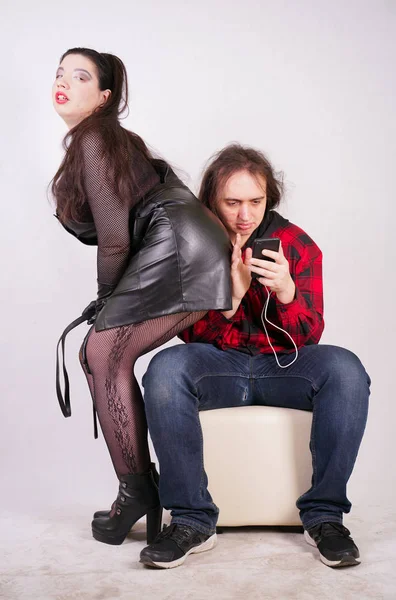 Atrakcyjna seksowna kobieta uwodzenie człowieka, podczas gdy on za pomocą smartfona — Zdjęcie stockowe