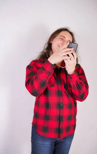 Dlouhý chlupový muž v Kostkové červené košili s telefonem na bílém pozadí ve studiu — Stock fotografie