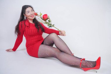 güzel mix kırmızı gül ile beyaz stüdyo arka plan üzerinde oturan zarif kırmızı midi elbise artı boyutu kız yarıştı