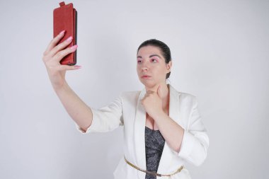 büyüleyici mix yarış artı beyaz bir iş ceketi boyutu kadın Studio beyaz arka planda elinde akıllı telefon ile selfie fotoğraf çekmek