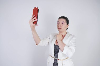 büyüleyici mix yarış artı beyaz bir iş ceketi boyutu kadın Studio beyaz arka planda elinde akıllı telefon ile selfie fotoğraf çekmek