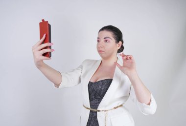 büyüleyici mix yarış artı beyaz bir iş ceketi boyutu kadın Studio beyaz arka planda elinde akıllı telefon ile görüntülü arama yapmak