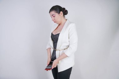 büyüleyici mix yarış artı beyaz bir iş ceketi studio beyaz arka plan üzerinde elinde akıllı telefon ile mutsuz ve üzgün ayakta boyutu kadın