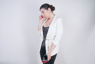 büyüleyici mix yarış artı beyaz bir iş ceketi studio beyaz arka plan üzerinde elinde akıllı telefon ile mutsuz ve üzgün ayakta boyutu kadın