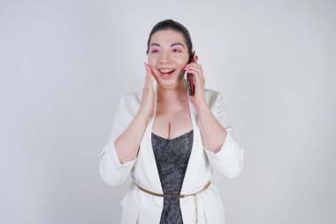 mutlu mix yarış artı beyaz bir iş ceketi arama ve Studio beyaz arka plan üzerinde elinde akıllı telefon ile konuşurken boyutu kadın
