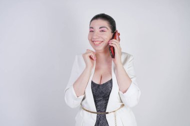 mutlu mix yarış artı beyaz bir iş ceketi arama ve Studio beyaz arka plan üzerinde elinde akıllı telefon ile konuşurken boyutu kadın