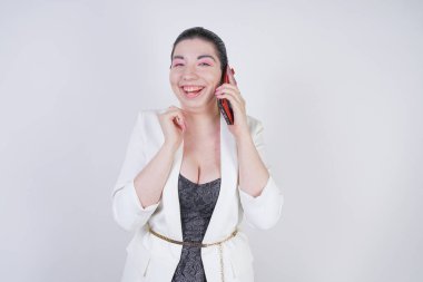 mutlu mix yarış artı beyaz bir iş ceketi arama ve Studio beyaz arka plan üzerinde elinde akıllı telefon ile konuşurken boyutu kadın