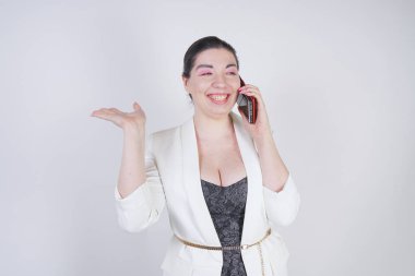 mutlu mix yarış artı beyaz bir iş ceketi arama ve Studio beyaz arka plan üzerinde elinde akıllı telefon ile konuşurken boyutu kadın