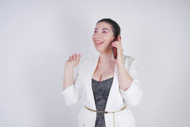 mutlu mix yarış artı beyaz bir iş ceketi arama ve Studio beyaz arka plan üzerinde elinde akıllı telefon ile konuşurken boyutu kadın