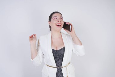 mutlu mix yarış artı beyaz bir iş ceketi arama ve Studio beyaz arka plan üzerinde elinde akıllı telefon ile konuşurken boyutu kadın