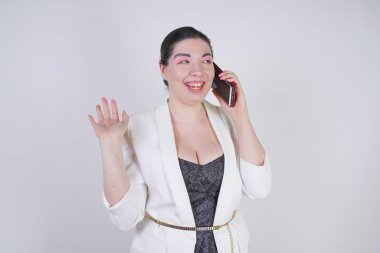 mutlu mix yarış artı beyaz bir iş ceketi arama ve Studio beyaz arka plan üzerinde elinde akıllı telefon ile konuşurken boyutu kadın