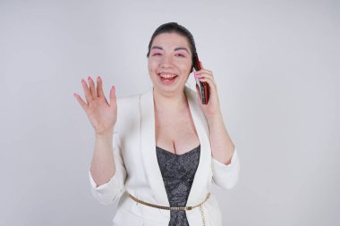 mutlu mix yarış artı beyaz bir iş ceketi arama ve Studio beyaz arka plan üzerinde elinde akıllı telefon ile konuşurken boyutu kadın