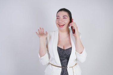 mutlu mix yarış artı beyaz bir iş ceketi arama ve Studio beyaz arka plan üzerinde elinde akıllı telefon ile konuşurken boyutu kadın