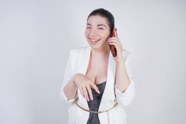mutlu mix yarış artı beyaz bir iş ceketi arama ve Studio beyaz arka plan üzerinde elinde akıllı telefon ile konuşurken boyutu kadın