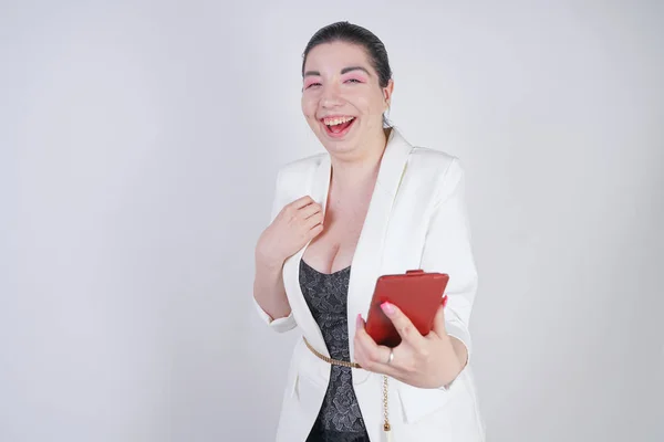 Charmante course de mélange plus la taille femme dans une veste d'affaires blanche faire appel vidéo avec téléphone intelligent à la main sur fond blanc dans Studio — Photo