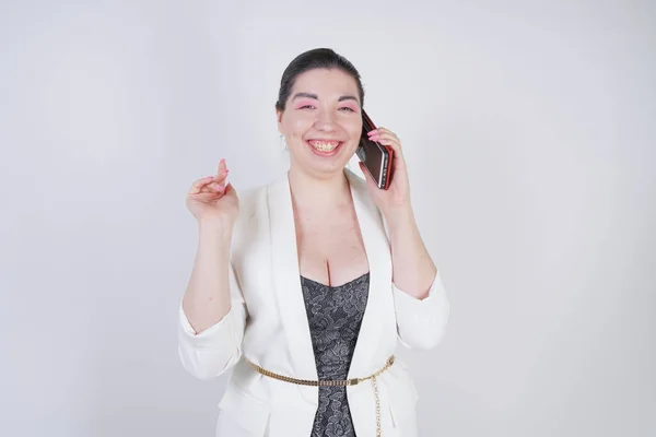 Happy mix race plus size woman in a white business jacket calling and talking by smartphone in hand on white background in Studio — Stock Photo, Image