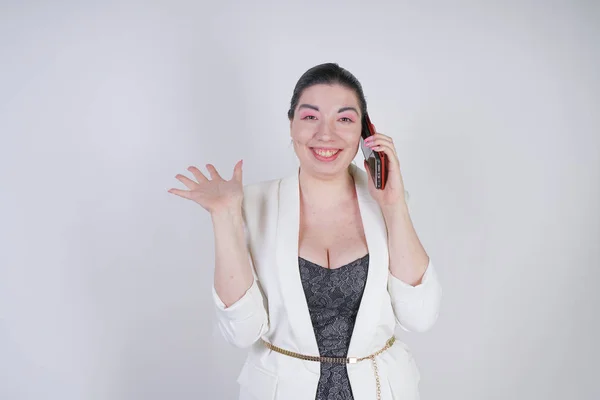 Happy mix race plus size woman in a white business jacket calling and talking by smartphone in hand on white background in Studio — Stock Photo, Image