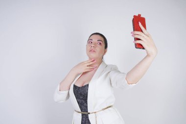 büyüleyici mix yarış artı studio beyaz arka plan üzerinde elinde akıllı telefon ile ayakta beyaz bir iş ceketi boyutu kadın