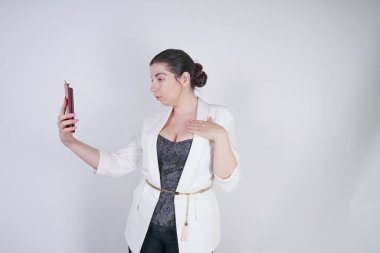 büyüleyici mix yarış artı studio beyaz arka plan üzerinde elinde akıllı telefon ile ayakta beyaz bir iş ceketi boyutu kadın