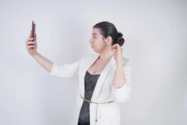 Charmante course de mélange plus la taille femme dans une veste d'affaires blanche debout avec téléphone intelligent à la main sur fond blanc dans Studio — Photo