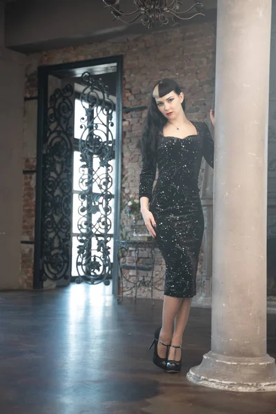 Готическая стройная кавказская девушка в черном обтягивающем платье позирует в своей комнате — стоковое фото