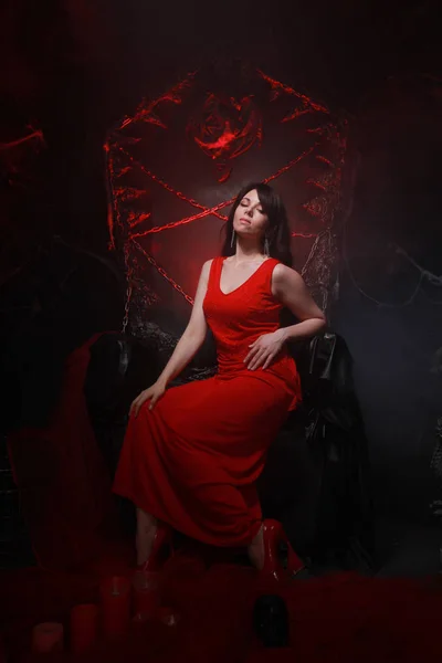 Beautiful lonely girl in long red dress on the halloween throne ready for scary party — Stock Photo, Image