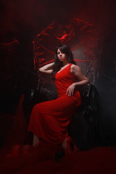 怖いパーティーの準備ができてハロウィーンの玉座に長い赤いドレスで美しい孤独な女の子 — ストック写真