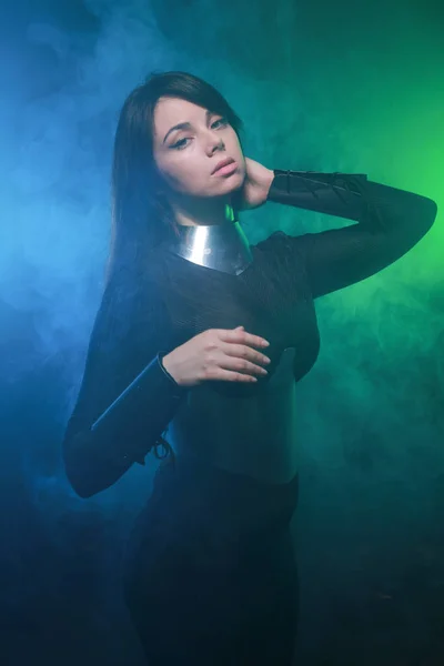 Futurisztikus divatmodell visel, fekete és ezüst ruhát, és állva a színes kék és zöld füst — Stock Fotó