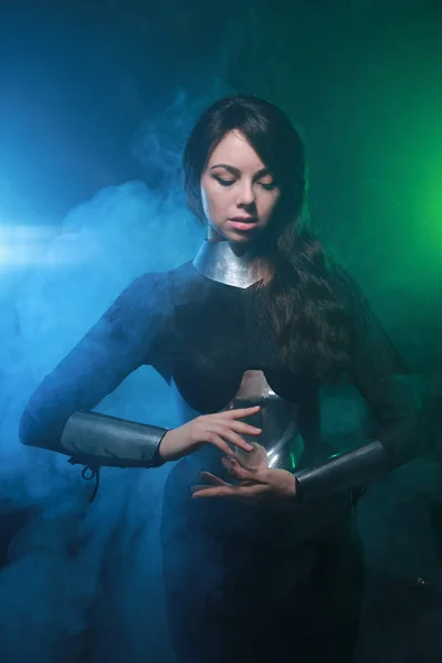 Modelo de moda futurista con ropa negra y plateada y de pie en el colorido humo azul y verde —  Fotos de Stock