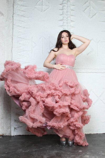 Портрет модной молодой девушки в длинном вечернем розовом платье
