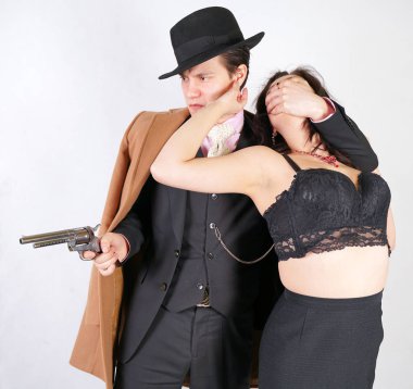 Silahlı bir adam bir kadını rehin aldı ve beyaz stüdyo arka planında ona işkence ediyor.