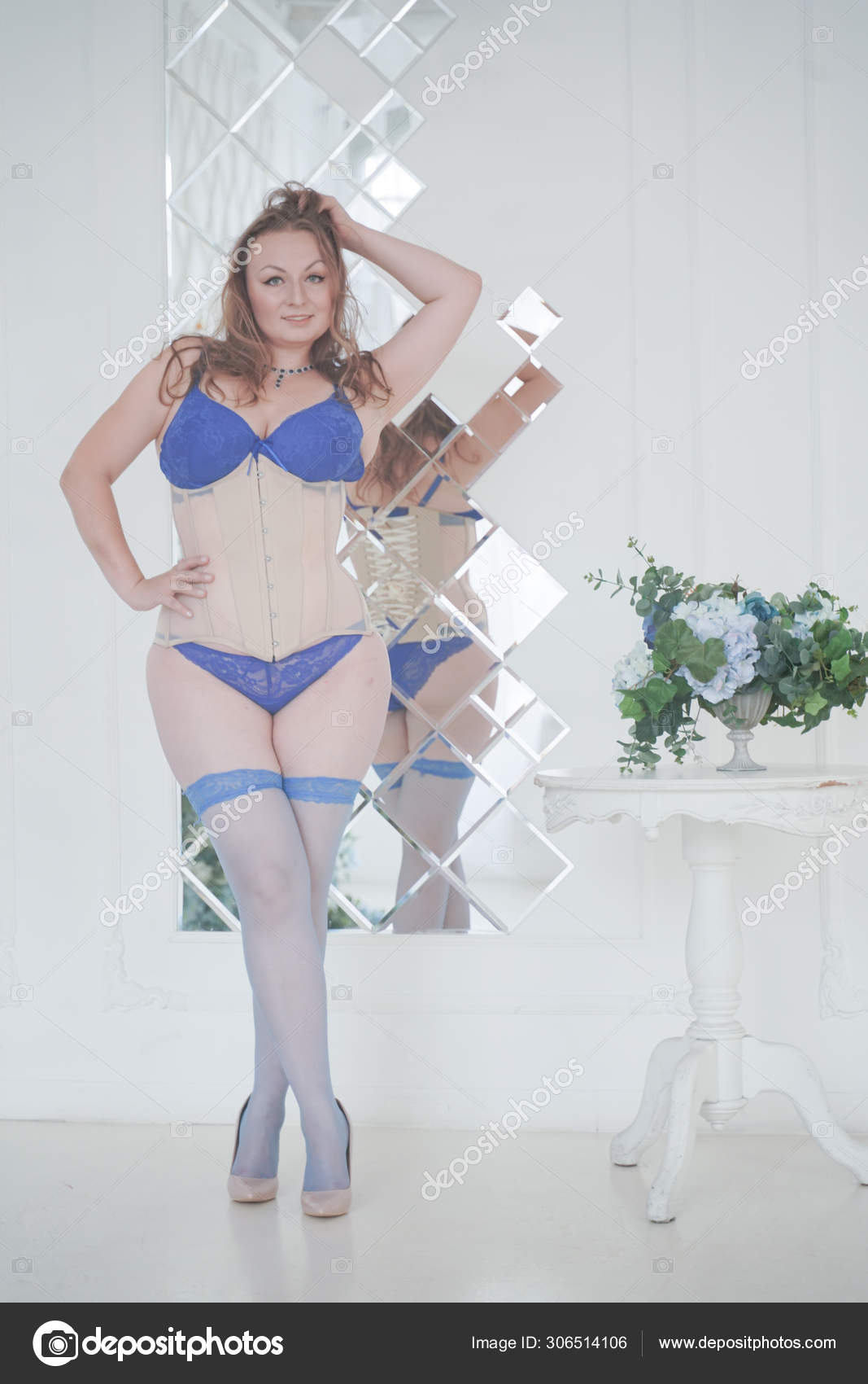 Pretty chubby woman in fashion blue lingerie in her white room