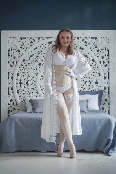 Sexuelle mariée plus la taille fille en lingerie blanche dans la chambre à coucher seule. femme potelée en dentelle sous-vêtements avec corset et bas seul — Photo