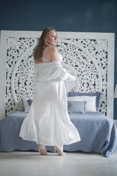 Sessuale plus size sposa ragazza in lingerie bianca in camera da letto da solo. paffuto donna in pizzo biancheria intima con corsetto e calze da solo — Foto Stock