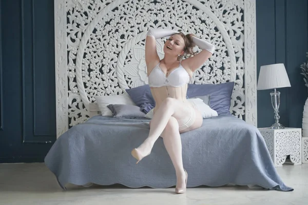 Sessuale plus size sposa ragazza in lingerie bianca in camera da letto da solo. paffuto donna in pizzo biancheria intima con corsetto e calze da solo — Foto Stock