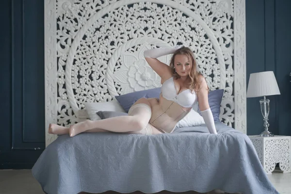 Chica novia más tamaño sexual en lencería blanca en el dormitorio solo. mujer gordita en ropa interior de encaje con corsé y medias solo — Foto de Stock