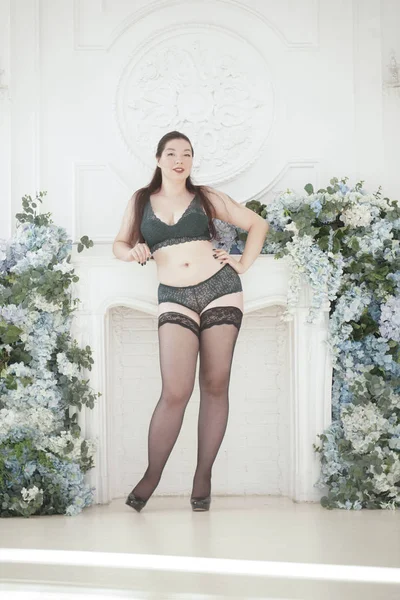 Feliz plus size mix raça mulher posando na moda lingerie e meias dentro de casa em apartamento branco sozinho — Fotografia de Stock