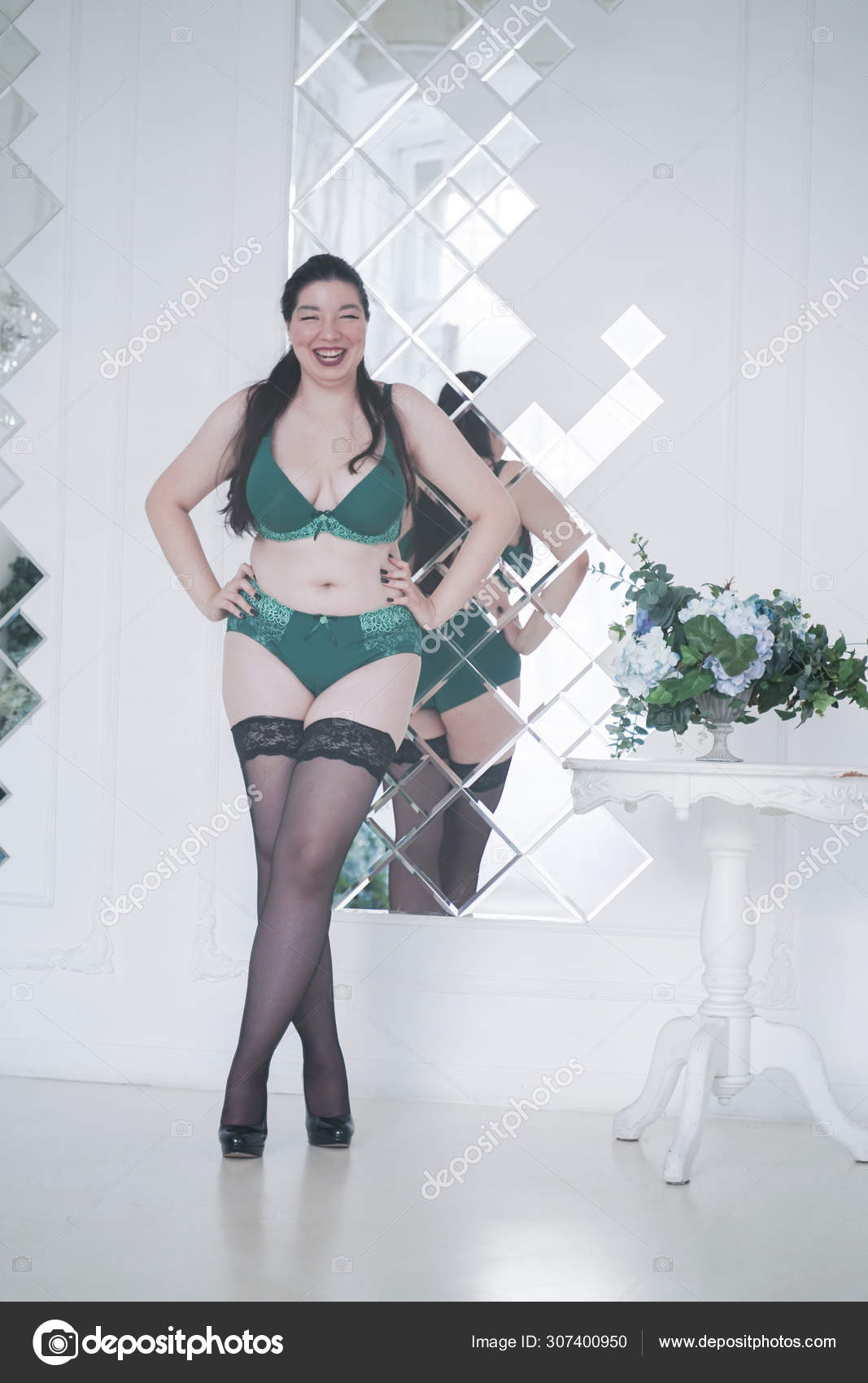 Happy plus size mix race woman posing in fashion lingerie and stockings  indoors in white apartment alone Stock Photo by ©agnadevi 307400950