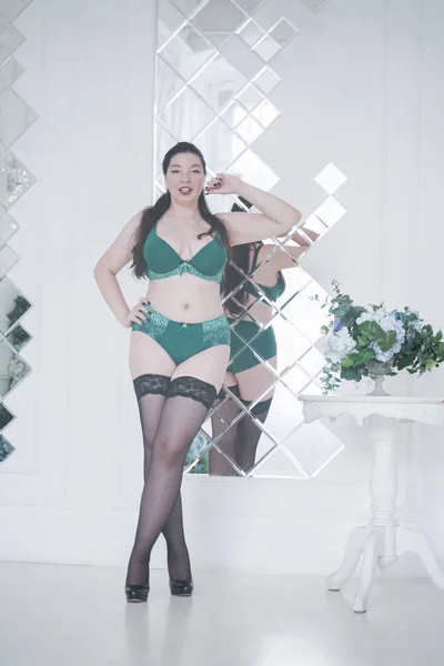 Feliz plus size mix raça mulher posando na moda lingerie e meias dentro de casa em apartamento branco sozinho — Fotografia de Stock