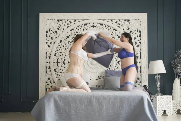 Además las mujeres de tamaño tienen pelea de almohadas en el dormitorio. gordito ladyes en lencería jugando . — Foto de Stock