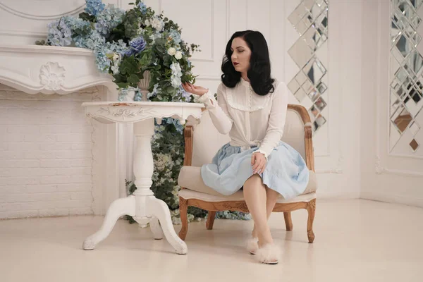 Pin up girl at a retro white apartment near the table. Pretty vintage woman in stylish room with flowers alone. — Stock Photo, Image