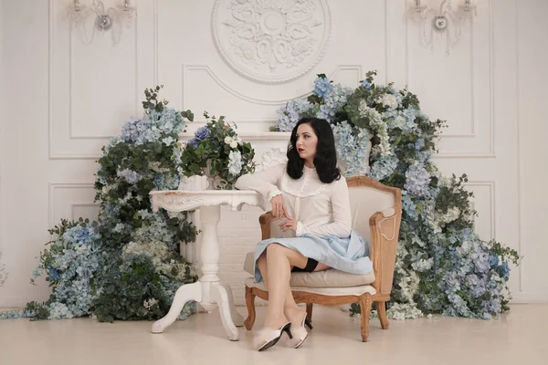 Pin up menina em um apartamento branco retro perto da mesa. Mulher vintage bonita em quarto elegante com flores sozinho . — Fotografia de Stock