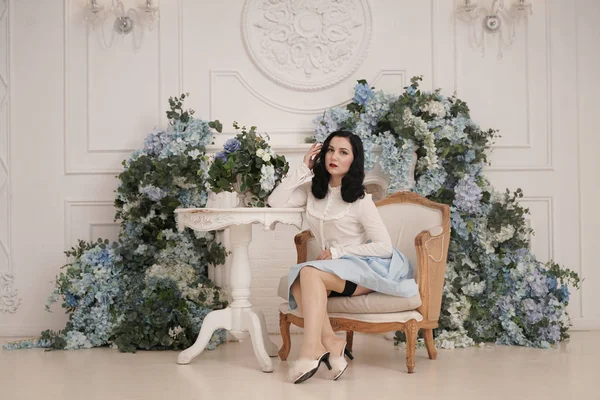 Pin up menina em um apartamento branco retro perto da mesa. Mulher vintage bonita em quarto elegante com flores sozinho . — Fotografia de Stock